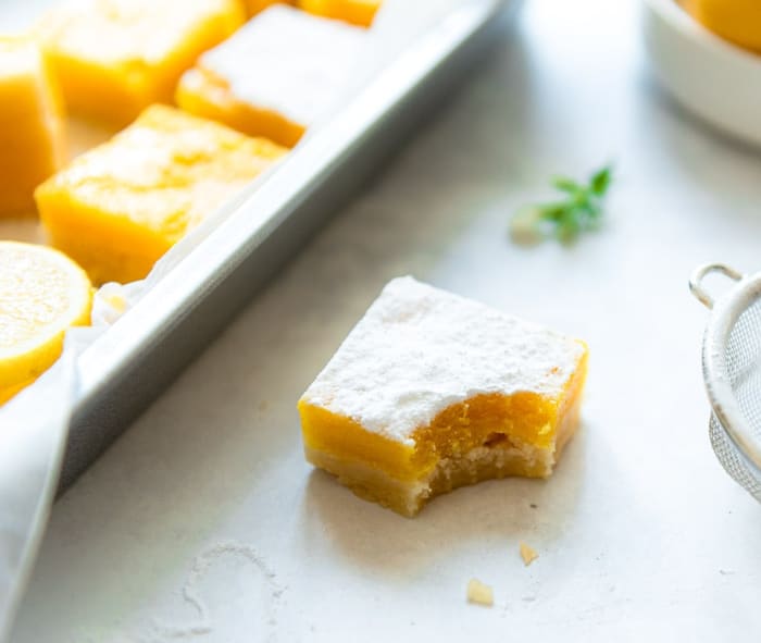 Lemon bar bestrooid met poedersuiker, met een hap eruit