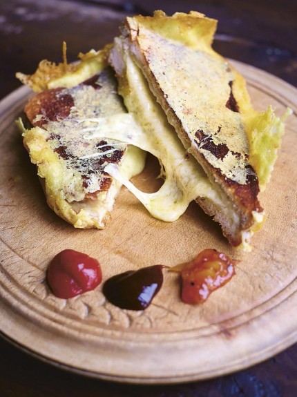 Doorgesneden Ultimate Cheese Toastie geserveerd met ketchup, worcestersaus en chutney
